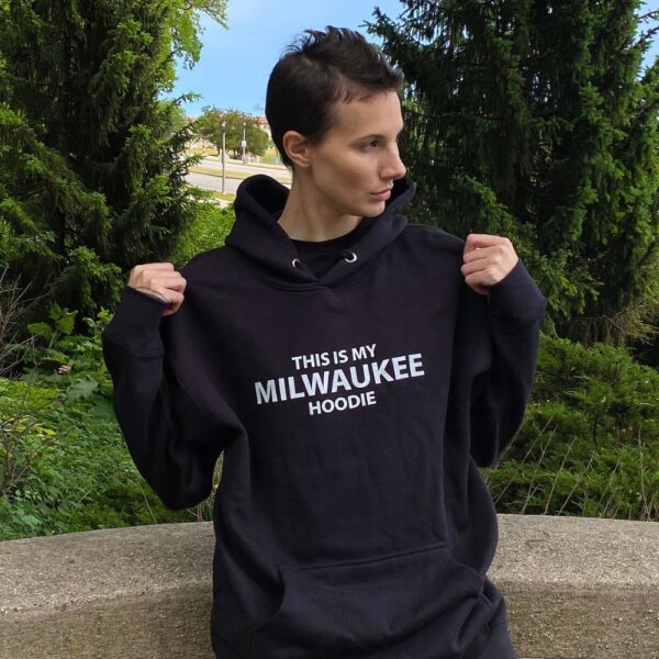 Woman wearing a black hoodie with white letters that read as, "This is my Milwaukee Hoodie" (yes, that's literally what it says).