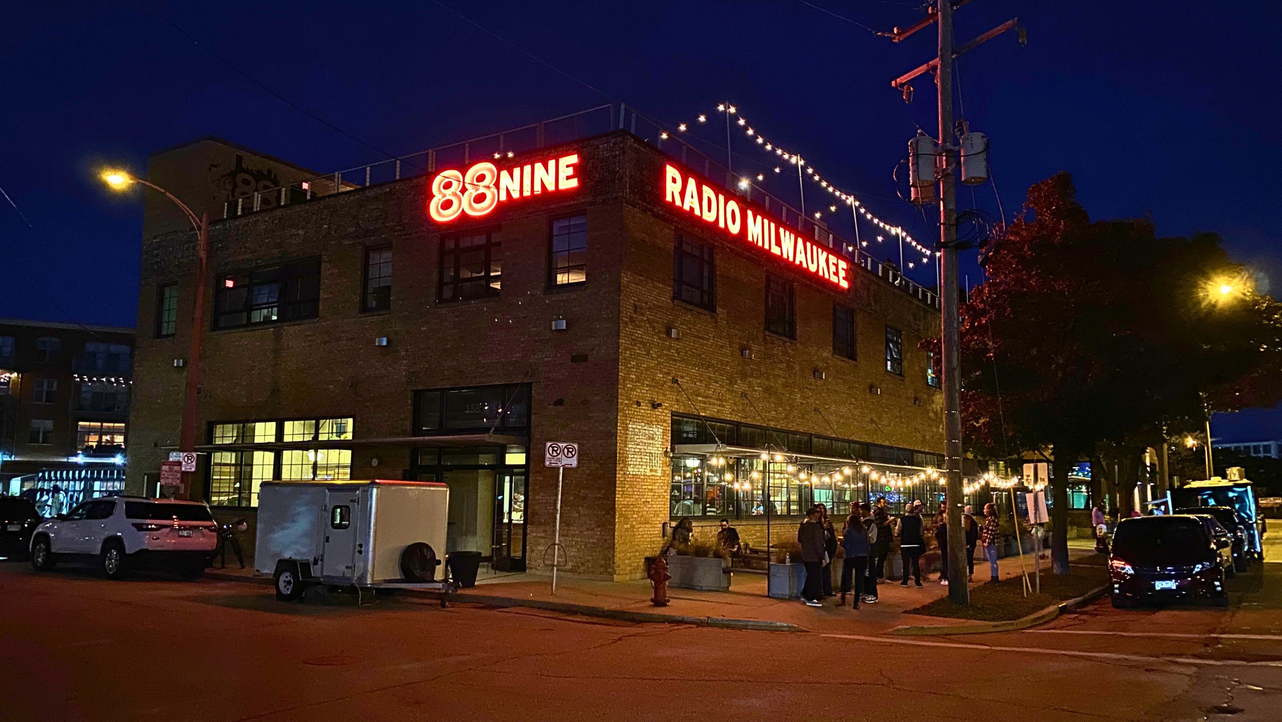 Exterior view of Radio Milwaukee's building at night with their neon signage lit red.