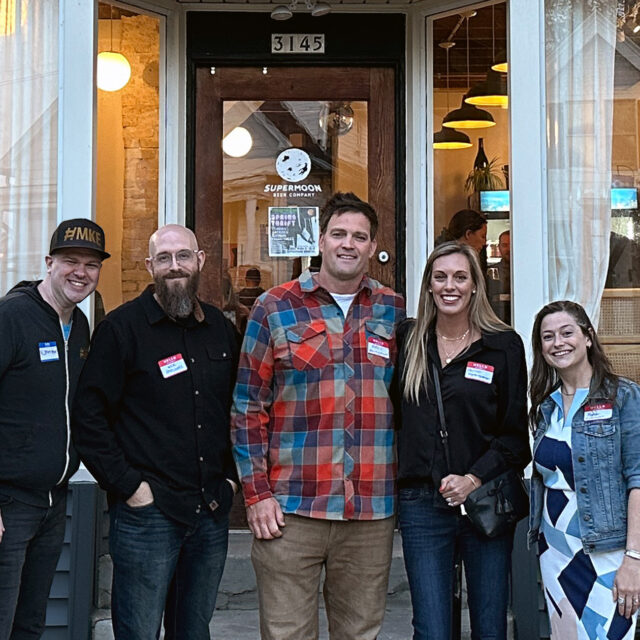 From left to right: JMatt, Nick of @Milweb1, Adam and Hannah of @GettingStamped, and Meg of @MilwaukeePhoto. Group of 5 people stand shoulder to shoulder outside of the main entrance to Supermoon Beer Company in Bay View.