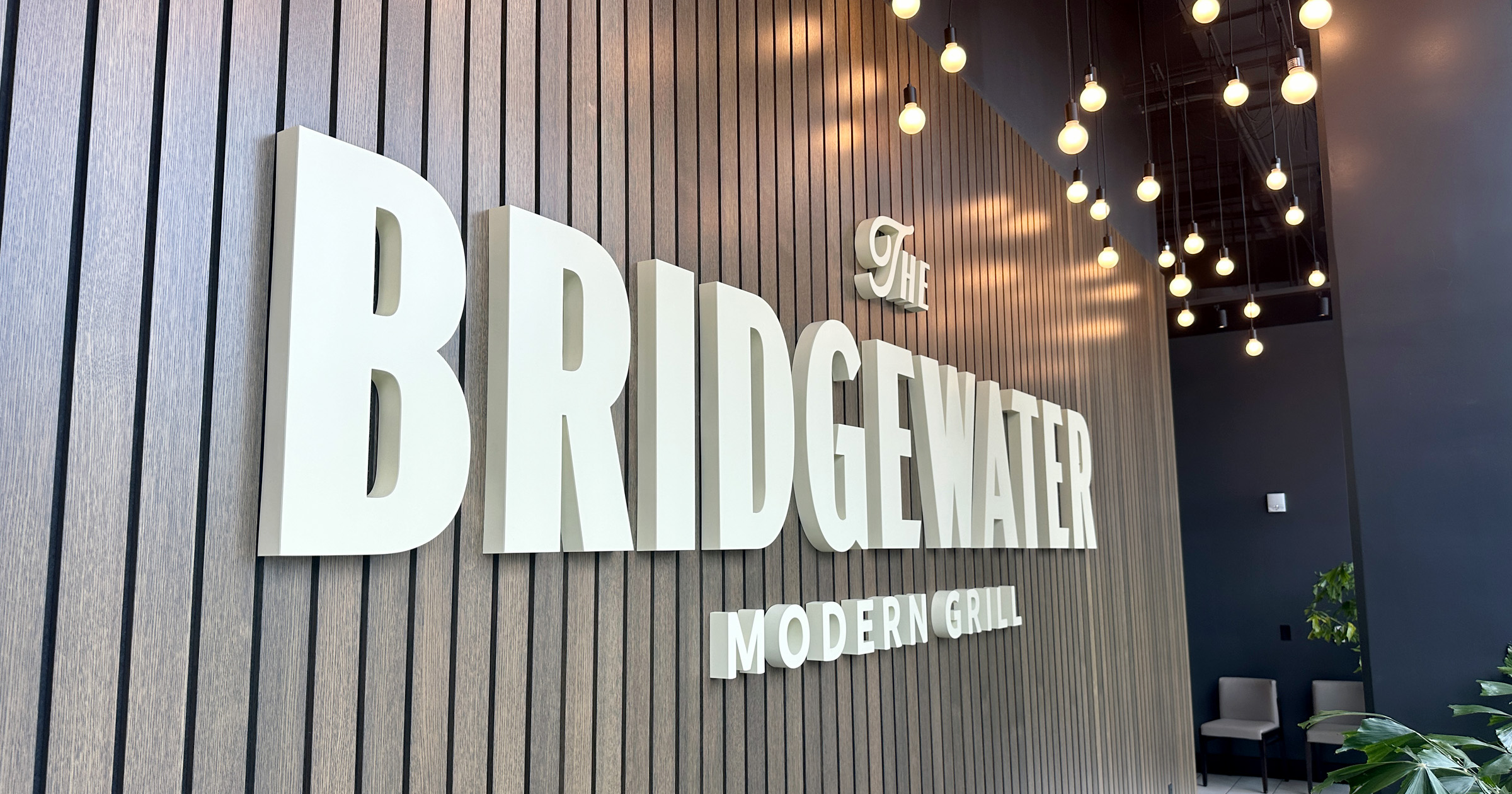 "The Bridgewater Modern Grill" white signage on a wooden slated wall.